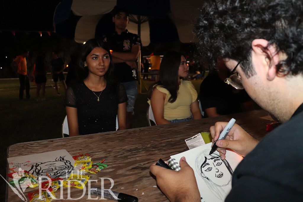 Zachary Arellano, an art education senior, draws a cartoon version of criminal justice freshman Evelyn Maciel at the Art Club booth Aug. 27 at The Stomp on the Student Union lawn on the Brownsville campus. Silvana Villarreal/THE RIDER